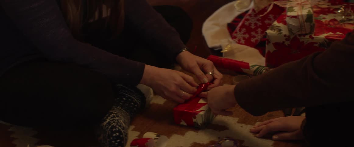 Two people wrap a christmas present together
