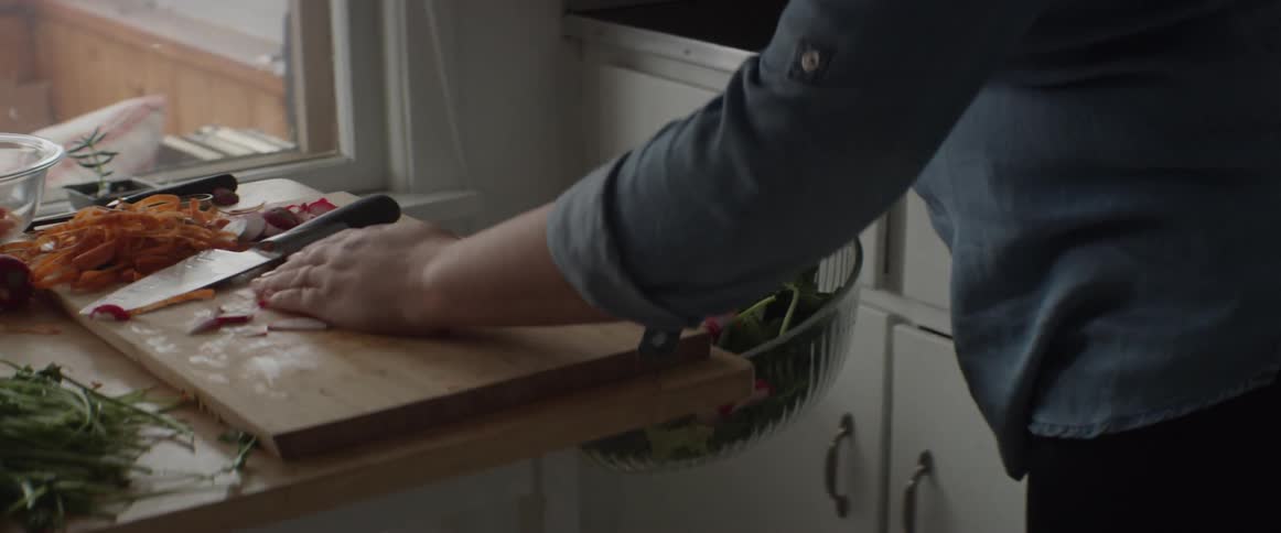 Woman sweeps food off a cutting board into a bowl
