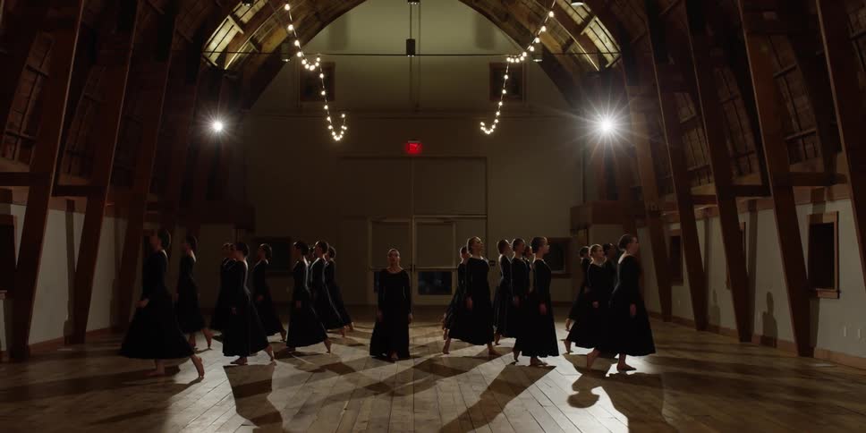 Women in black march ahead in the hall then begin dancing