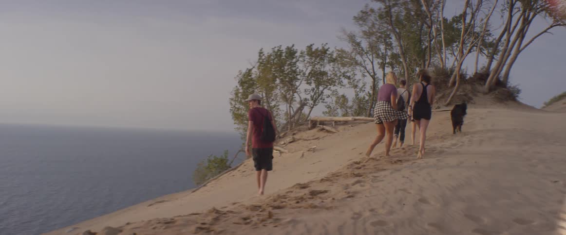 People walk on a sandy beach on a windy day