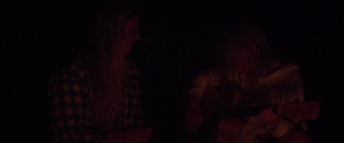 People play guitar by campfire