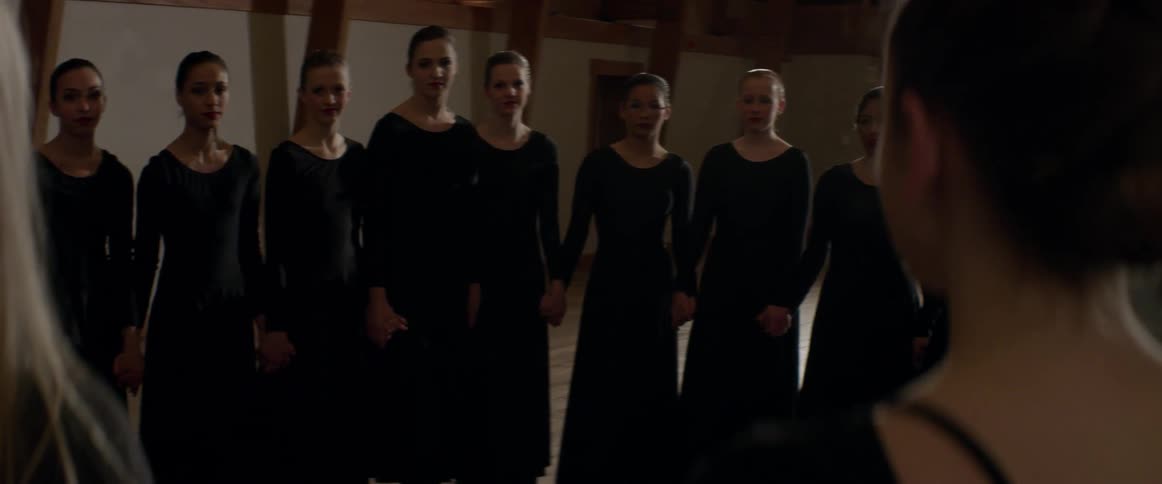 A row of women in black dresses hold hands
