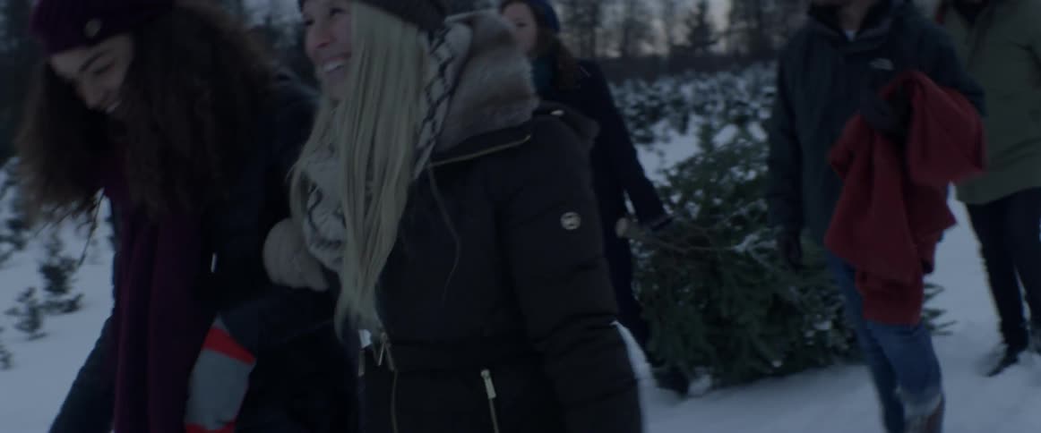 People laugh and talk as one drags a tree behind