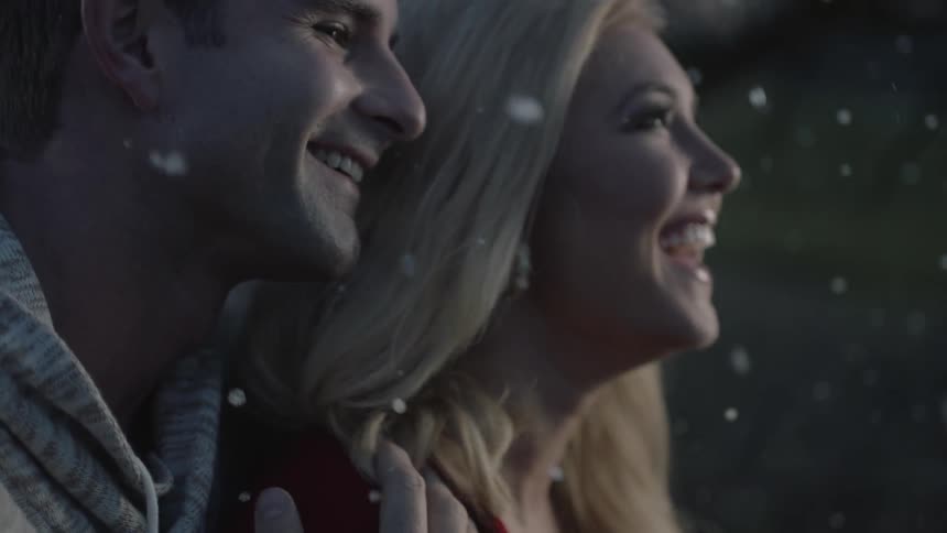 Man and woman cuddle and talk as snow falls around them