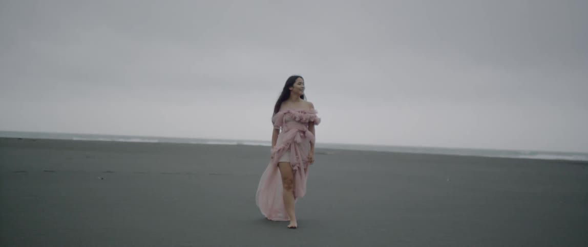 A woman in a dress walks on sand