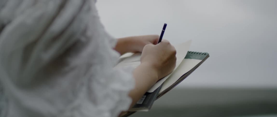 A person is writing on notebooks
