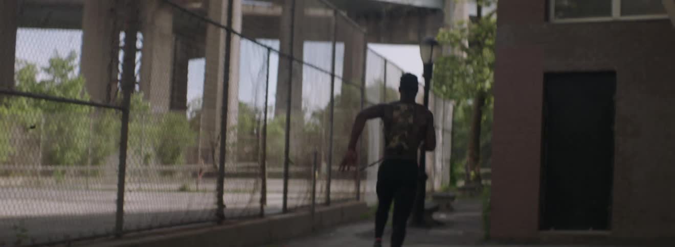 A shirtless man sprints through a city park