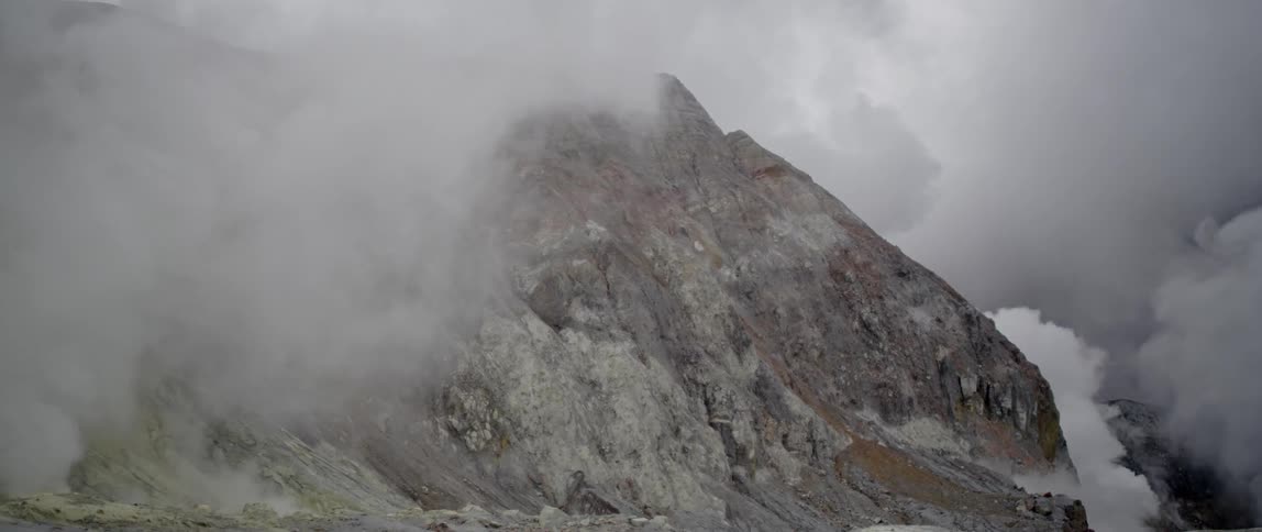 Clouds hover over a rocky mountain peak