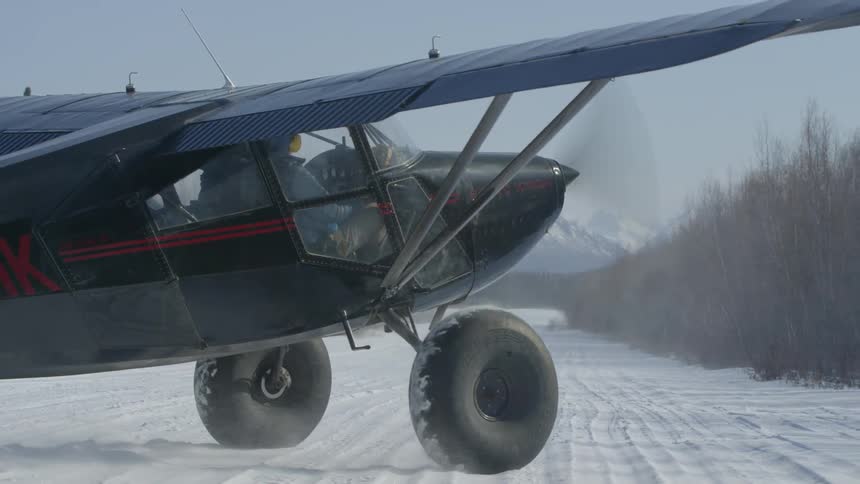Small prop plane slowly turning to face the long snowy runway