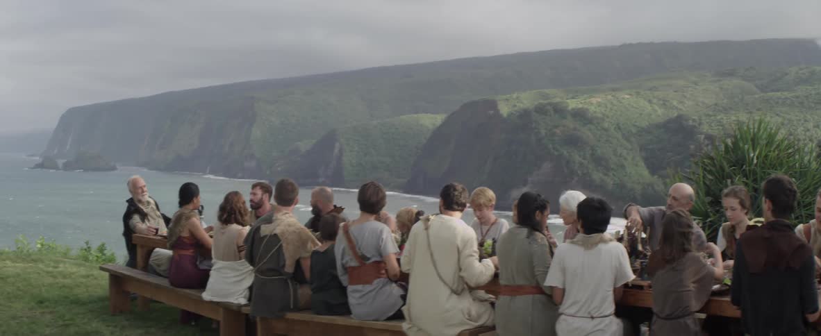 A group of people sit at a long table eating