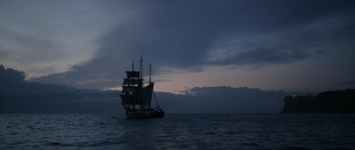 A ship with many sails is in the middle of the ocean