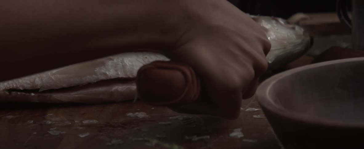 A person fillets a fresh fish using a knife