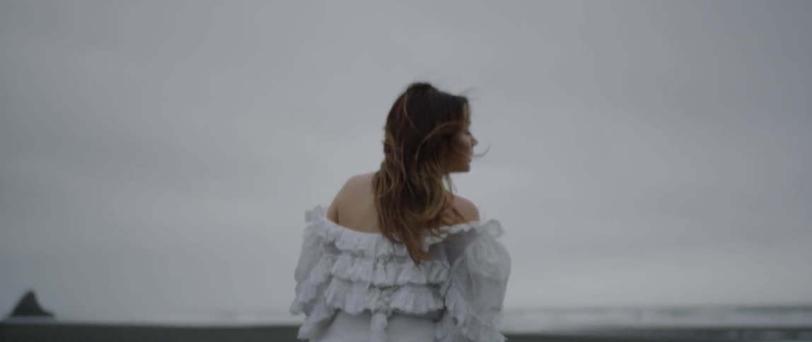 A woman tosses her hair as she walks on a beach