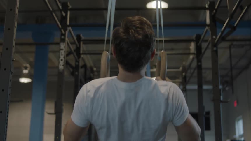 A man does pull ups on equipment in a gym