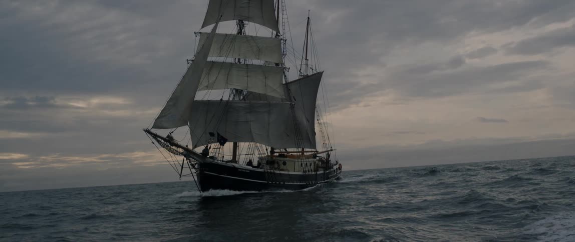 A ship sails on the open seas at sunset