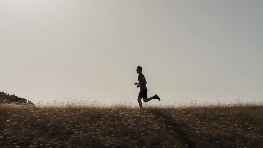 A man jogs along a grassy ridge