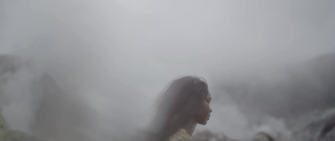 A woman walks in the mountains on a foggy day
