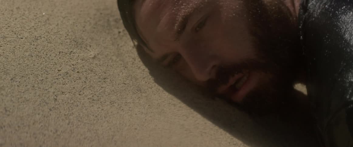 Waves splash over a man washed up on the sand