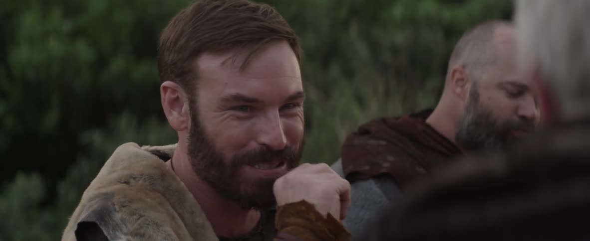 Two men are laughing about something while eating outdoors