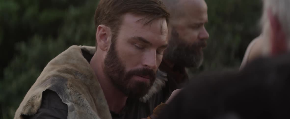 Two bearded men sit next to each other sipping drinks