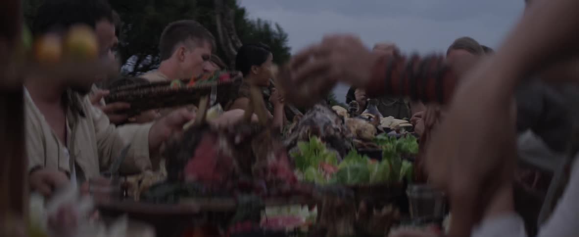 Large group of people eating outdoor near ocean on windy evening