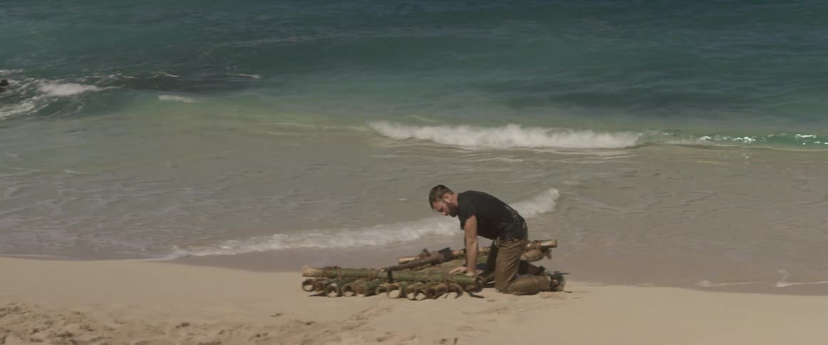 A man is leaning over a raft by the water