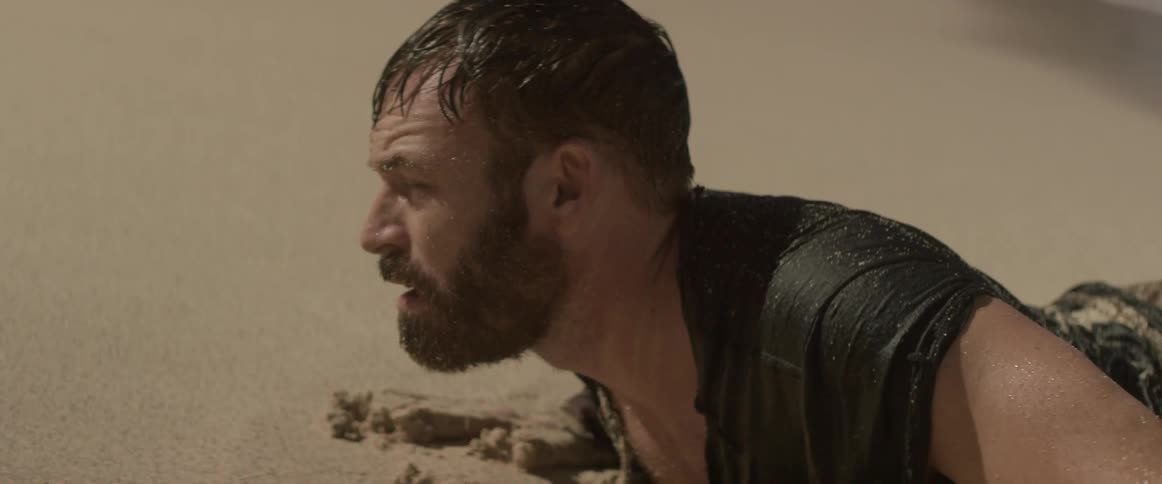 A man washed up on the beach wakes up and looks around