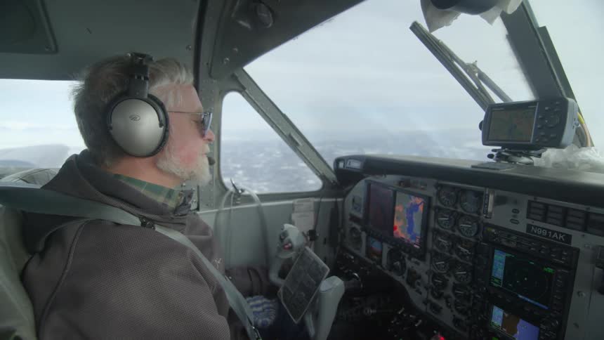 Man wearing headphones piloting an airplane