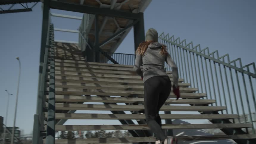 A woman sprints up stairs outside on a snowy day