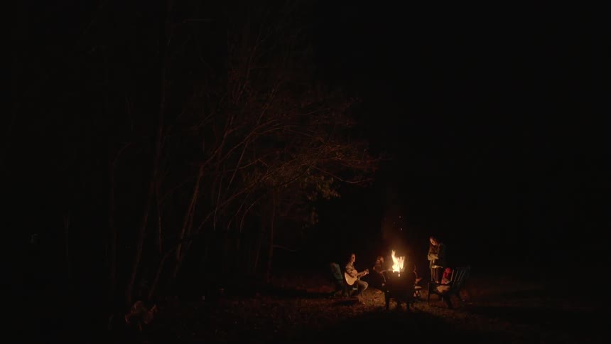 Dark area with people sitting around a campfire