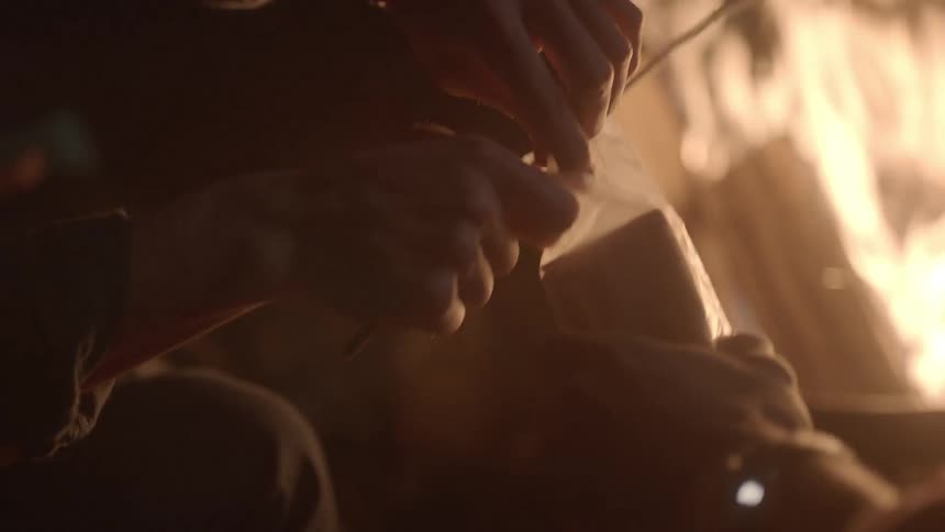 People sit around a campfire roasting marshmallows