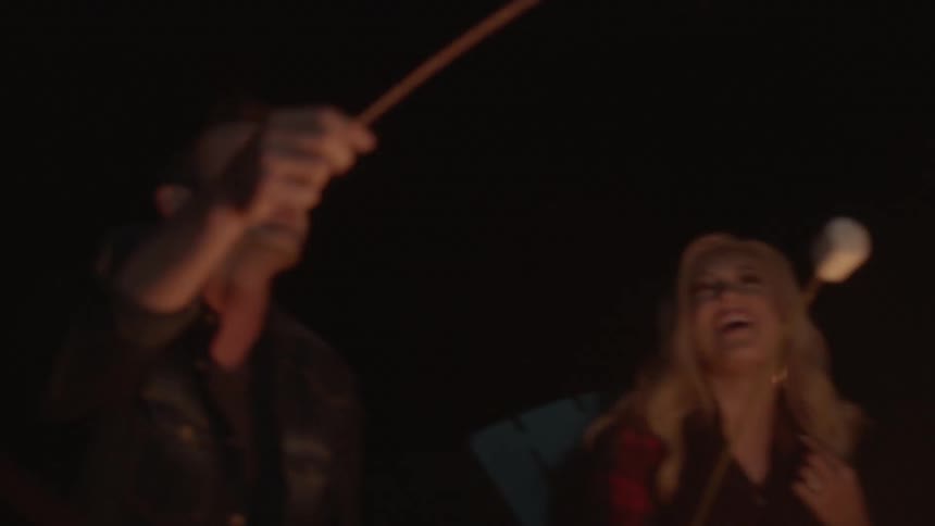 A group of people roasting marshmallows over a campfire