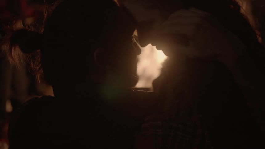 Man and woman hugging next to a campfire