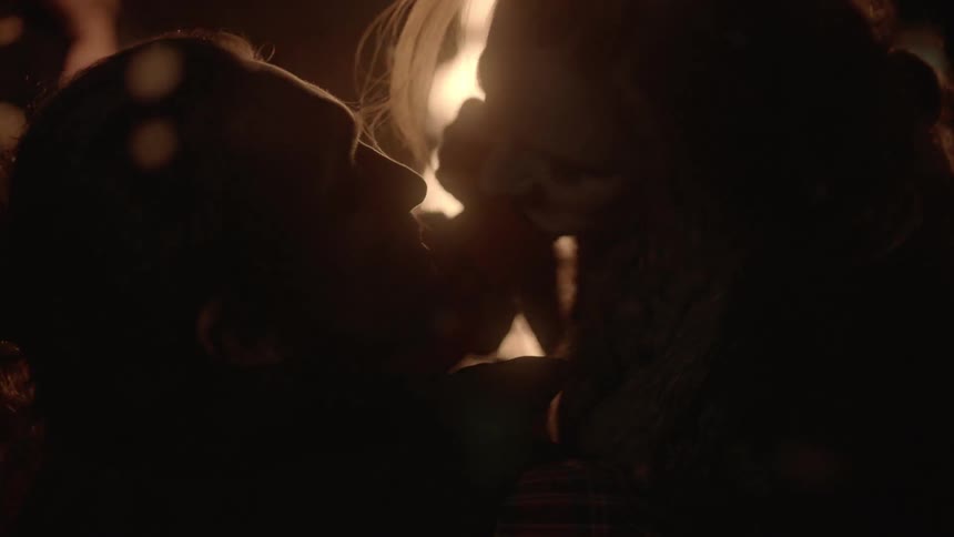 A couple kissing by a fire