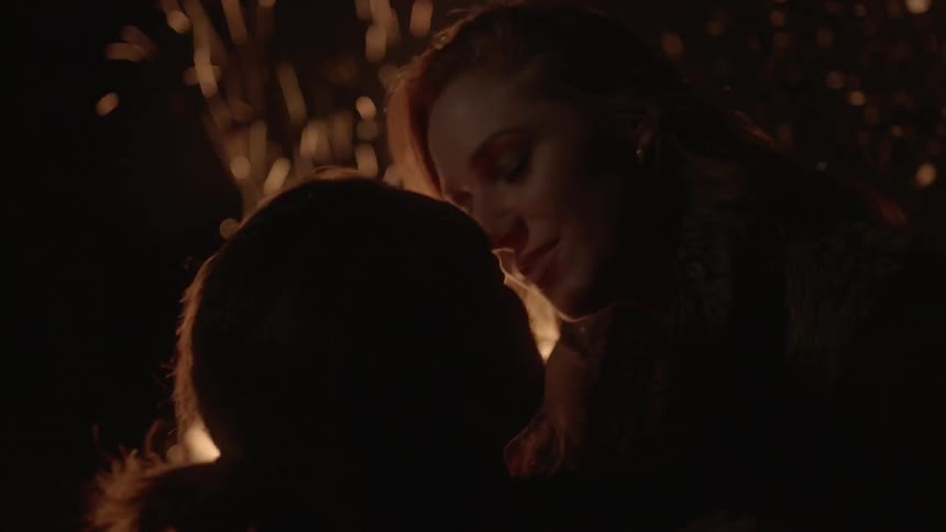 Man and woman kissing in front of a campfire