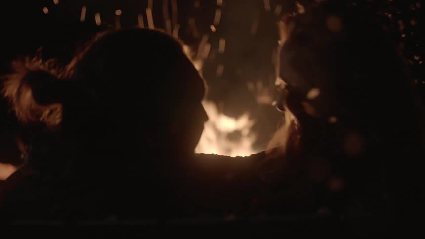 Man and woman hugging in front of a campfire