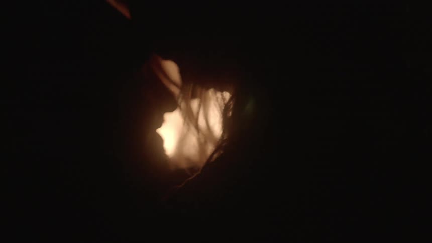 Man and woman cuddling in front of a campfire at night