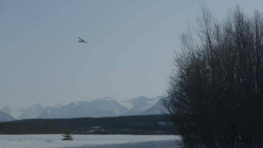 A plan flies high over some snow covered mountains
