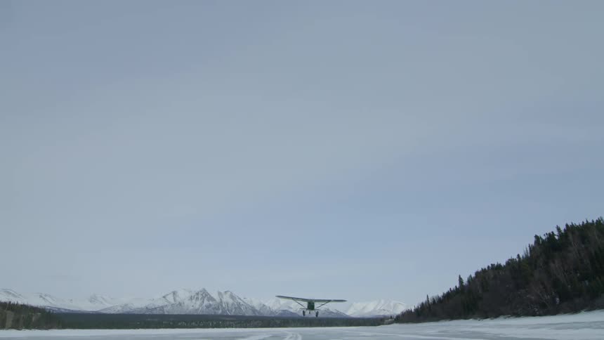 A small airplane takes off from a snow-covered field