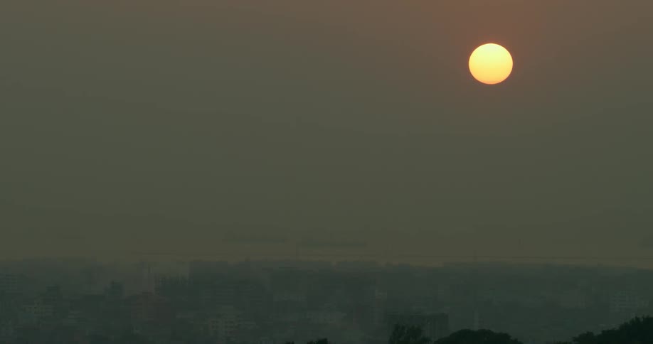 The sun shines a bright orange in the sky
