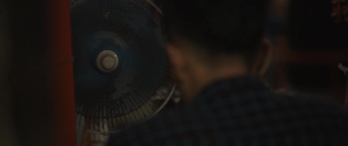 A man is standing looking at a fan