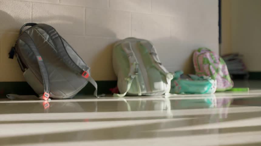 Three backpacks in a row in a school hallway