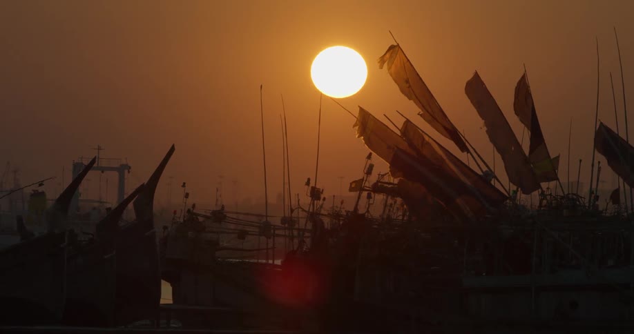 The sun sets over flags on poles