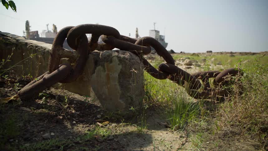 Large rusty chain lies on the grass on a clear day