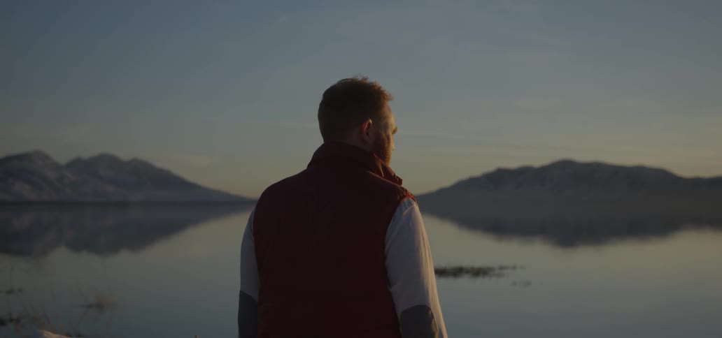 A man looks out over the lake at dawn