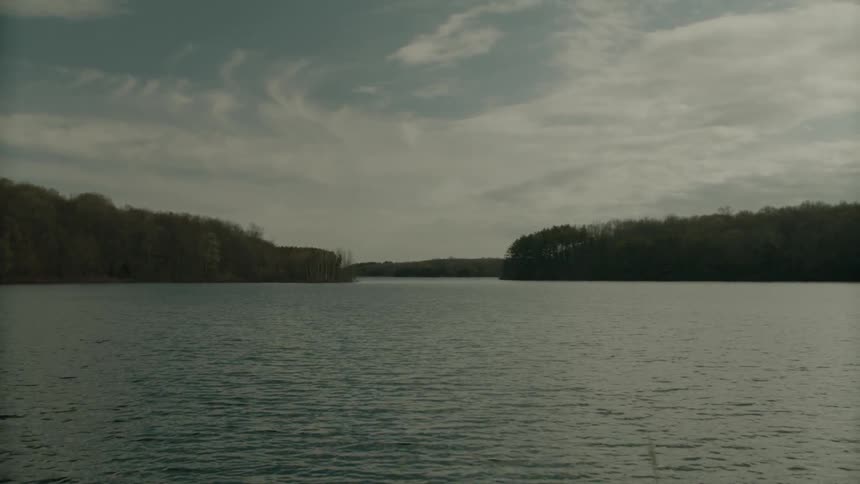 A lake surrounded by trees shimmers in the sunlight