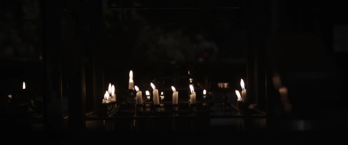 The dark hall has many candles on the ground