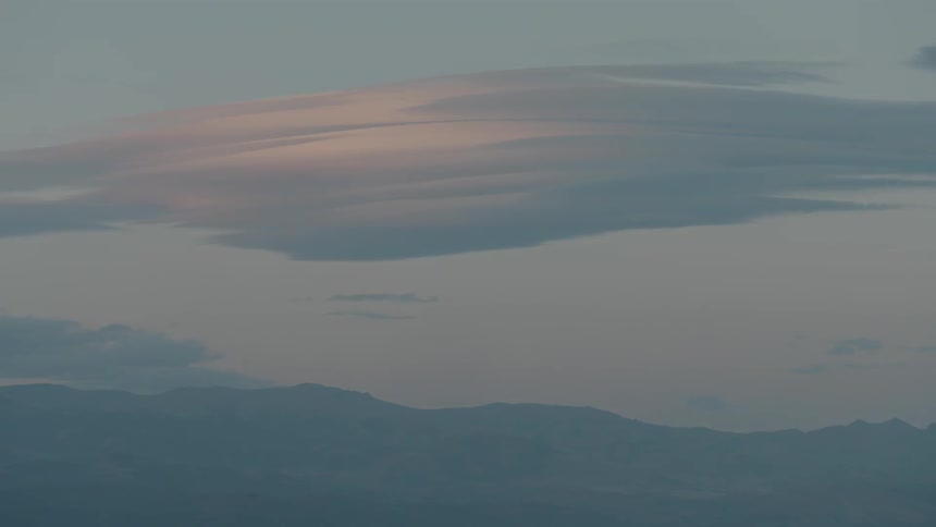Clouds float over mountains at sunset