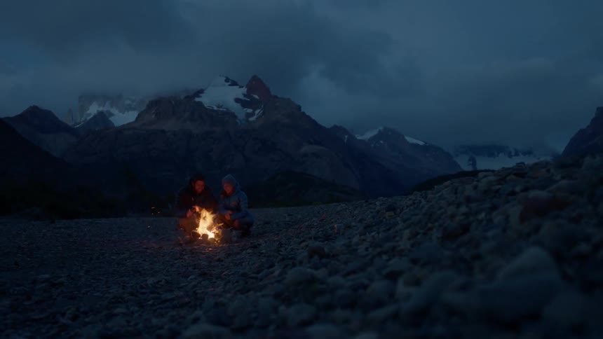 People sitting next to a campfire on a cloudy night