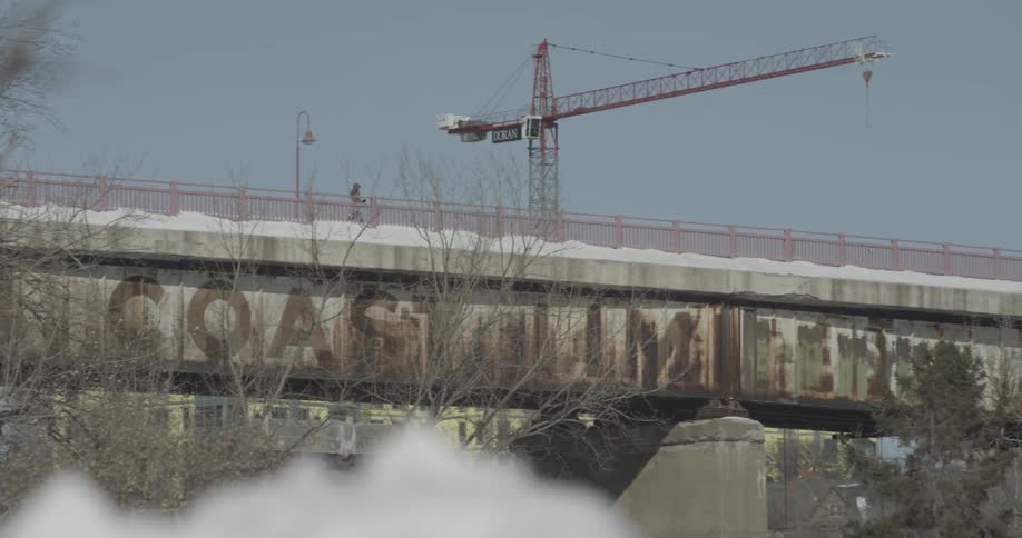 A jogger runs past a large crane on a snowy day
